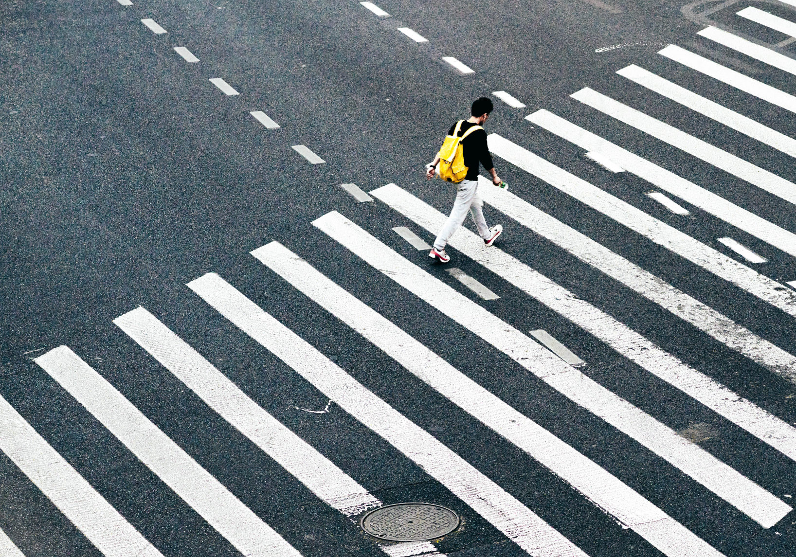guy with yellow backback walking across crosswalk | Qualitative Research Methods | Meeting Street Insights